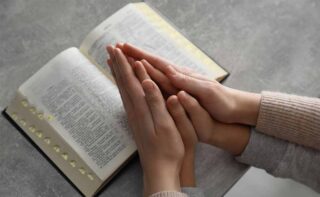 Boy,and,his,godparent,praying,together,at,grey,table,,closeup