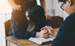 A group of Christians praying with Bible on table