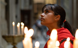 Teenage,girl,in,a,red,jacket,praying,in,a,church